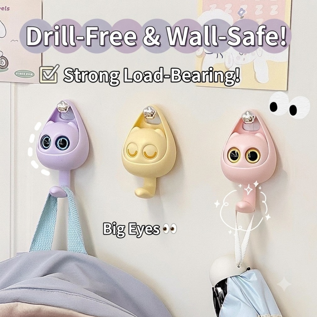Three cartoon-style wall hooks with big eyes on a light background, labeled 'Drill-Free & Wall-Safe' and 'Strong Load-Bearing'.